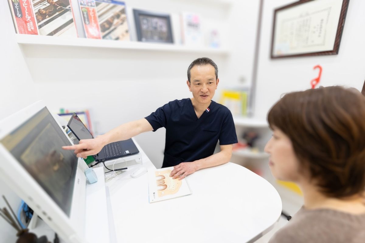 りんせんじ歯科の院長がパソコンの前で説明をしている