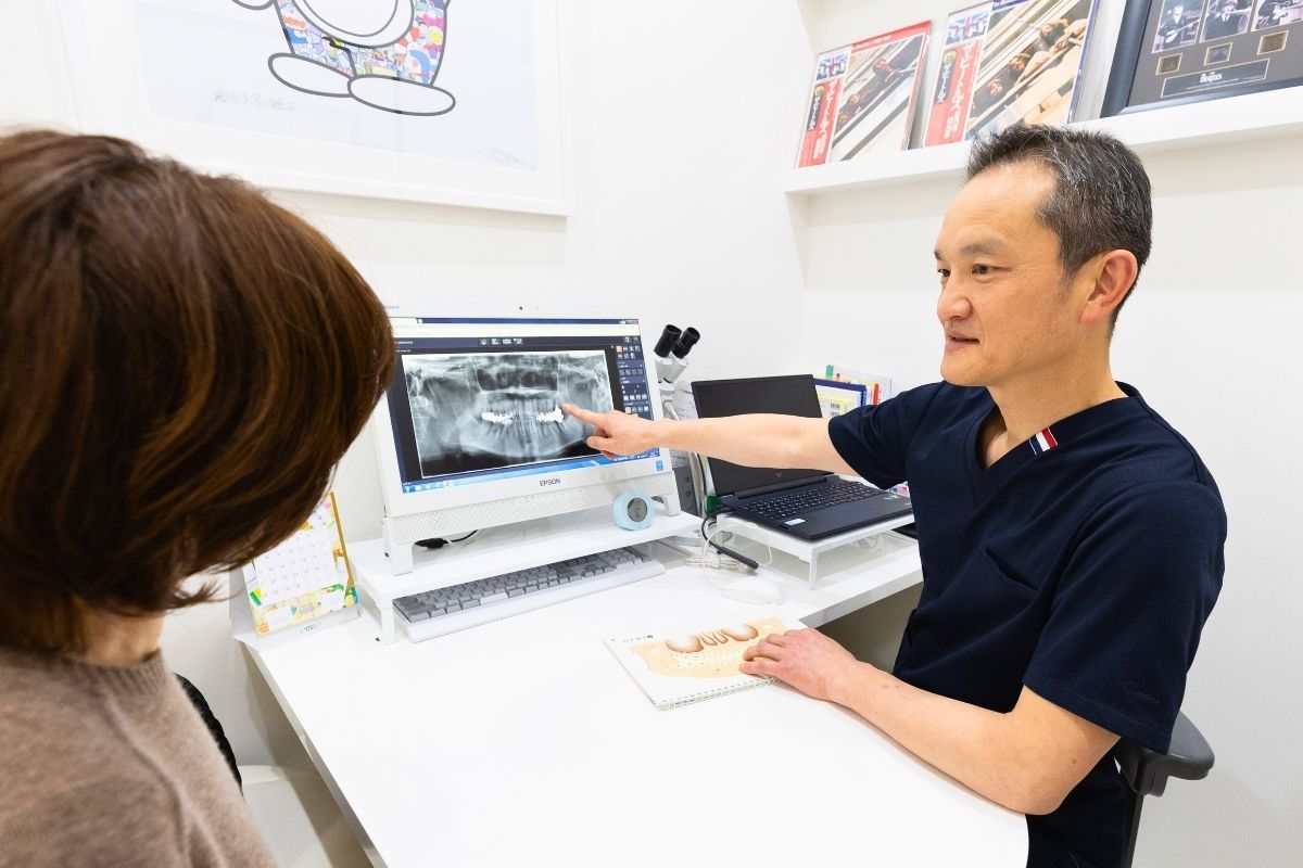 りんせんじ歯科の院長がモニターのレントゲンを指差しながら説明している